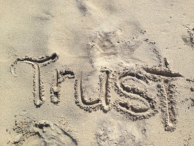 'Trust' written in sand