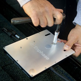 An enphase microinverter being bolted to the racking system