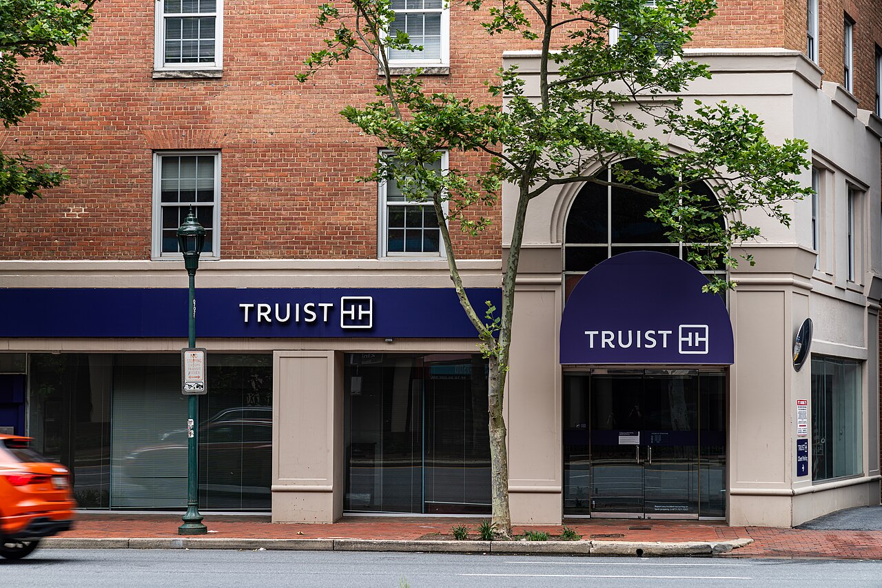 A Truist Bank branch with a brick facade and purple Truist signs on a city street corner