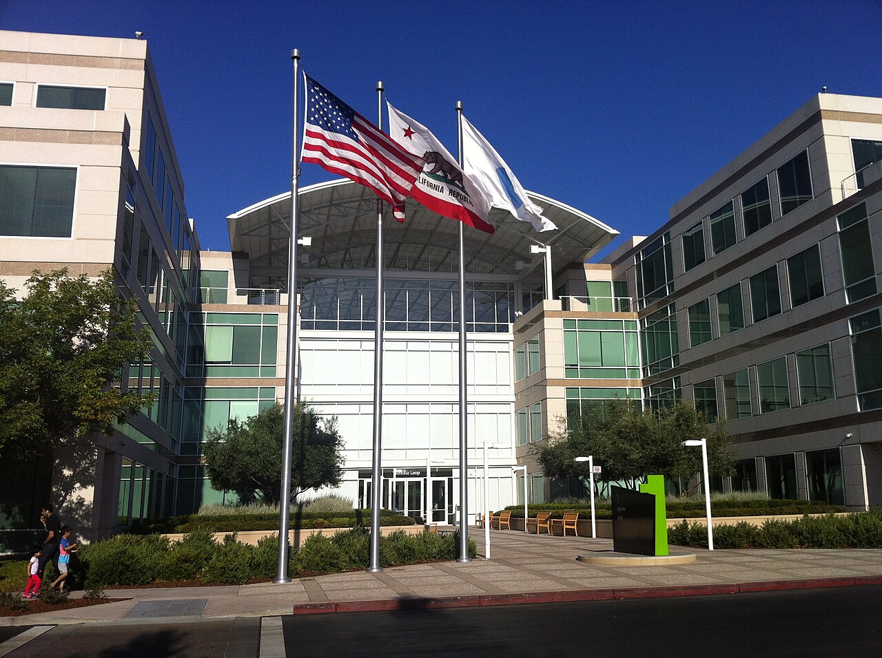An Apple office building at One Infinite Loop in Cupertino, California, with the United States and California flags in front