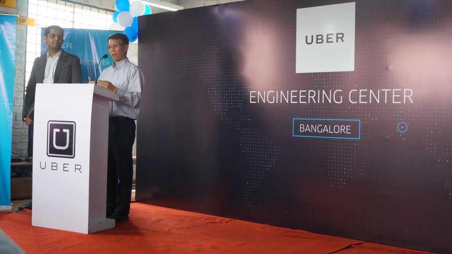 A speaker at a podium beside a backdrop reading Uber Engineering Center Bangalore